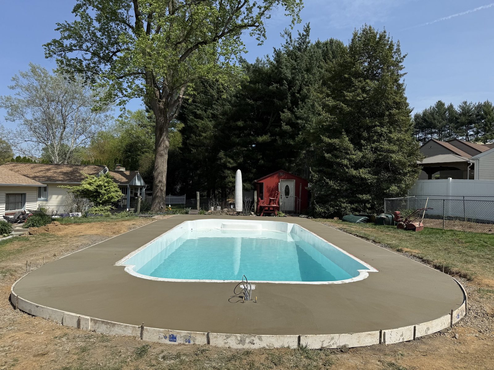 Concrete pool deck surrounding a backyard swimming pool