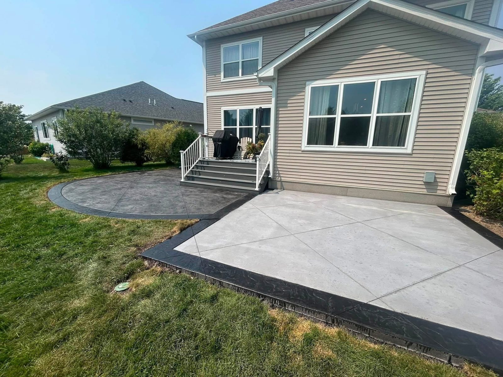 Wide view of a two-tone concrete patio behind a home