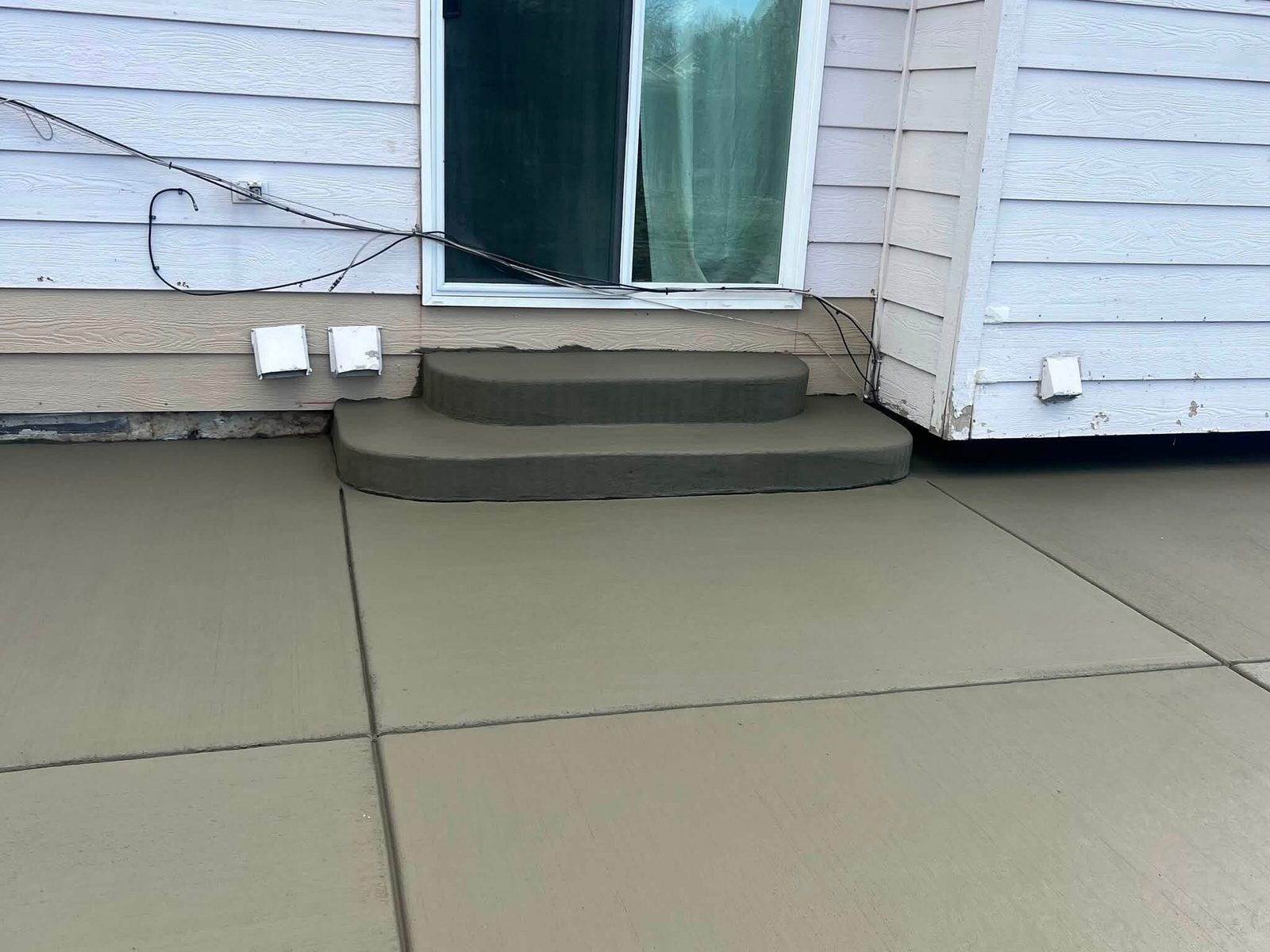Brushed concrete patio surrounding a set of exterior steps