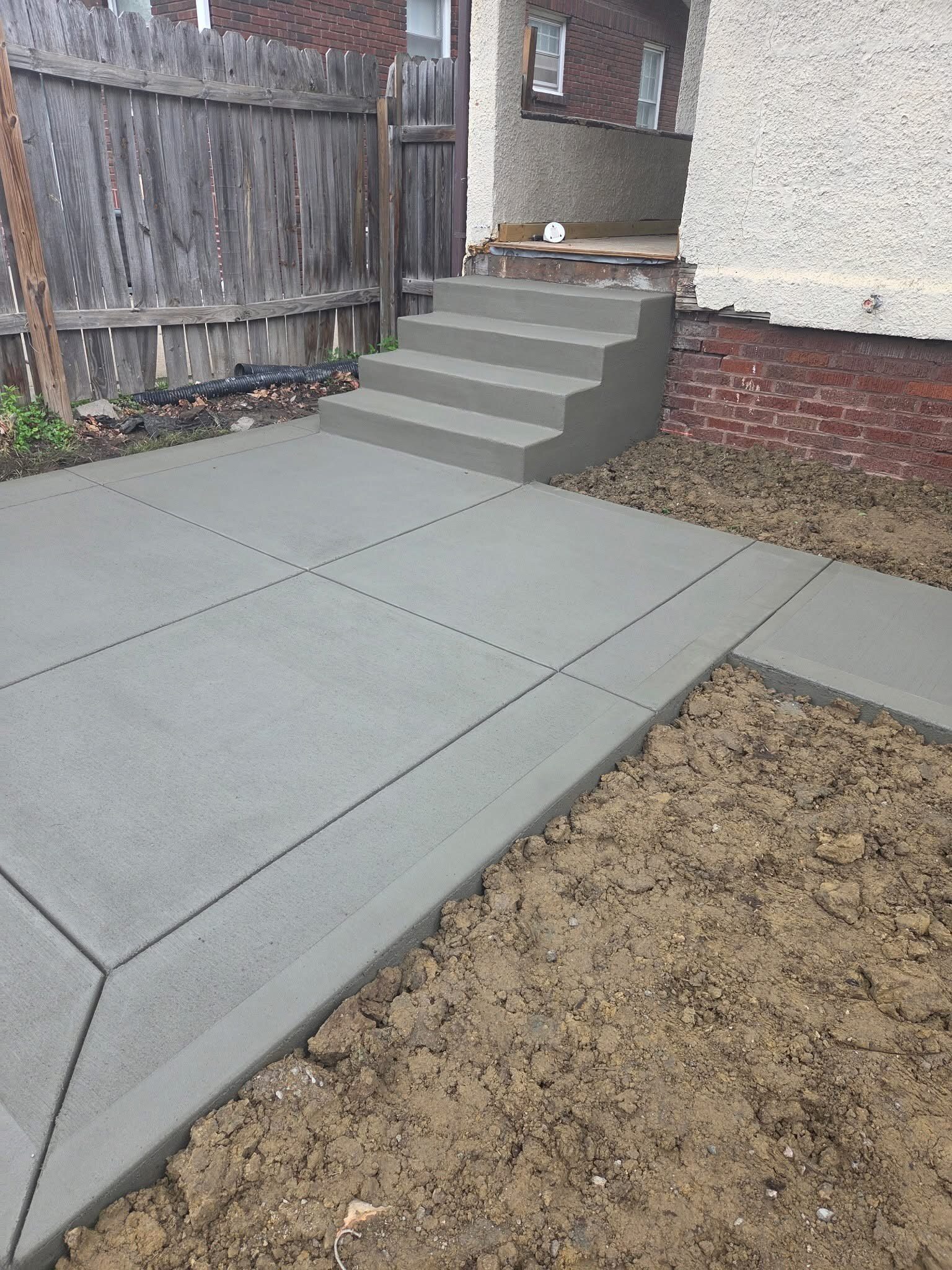 Concrete patio and finished steps at the back of a home