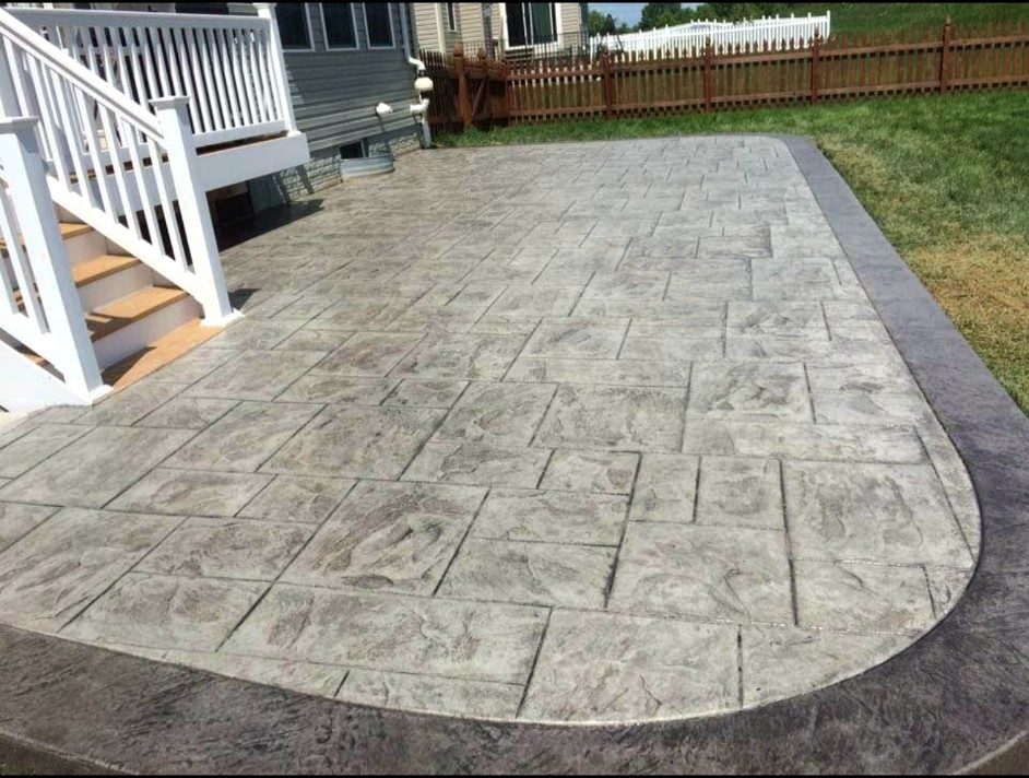 Curved stamped concrete patio beside a raised deck