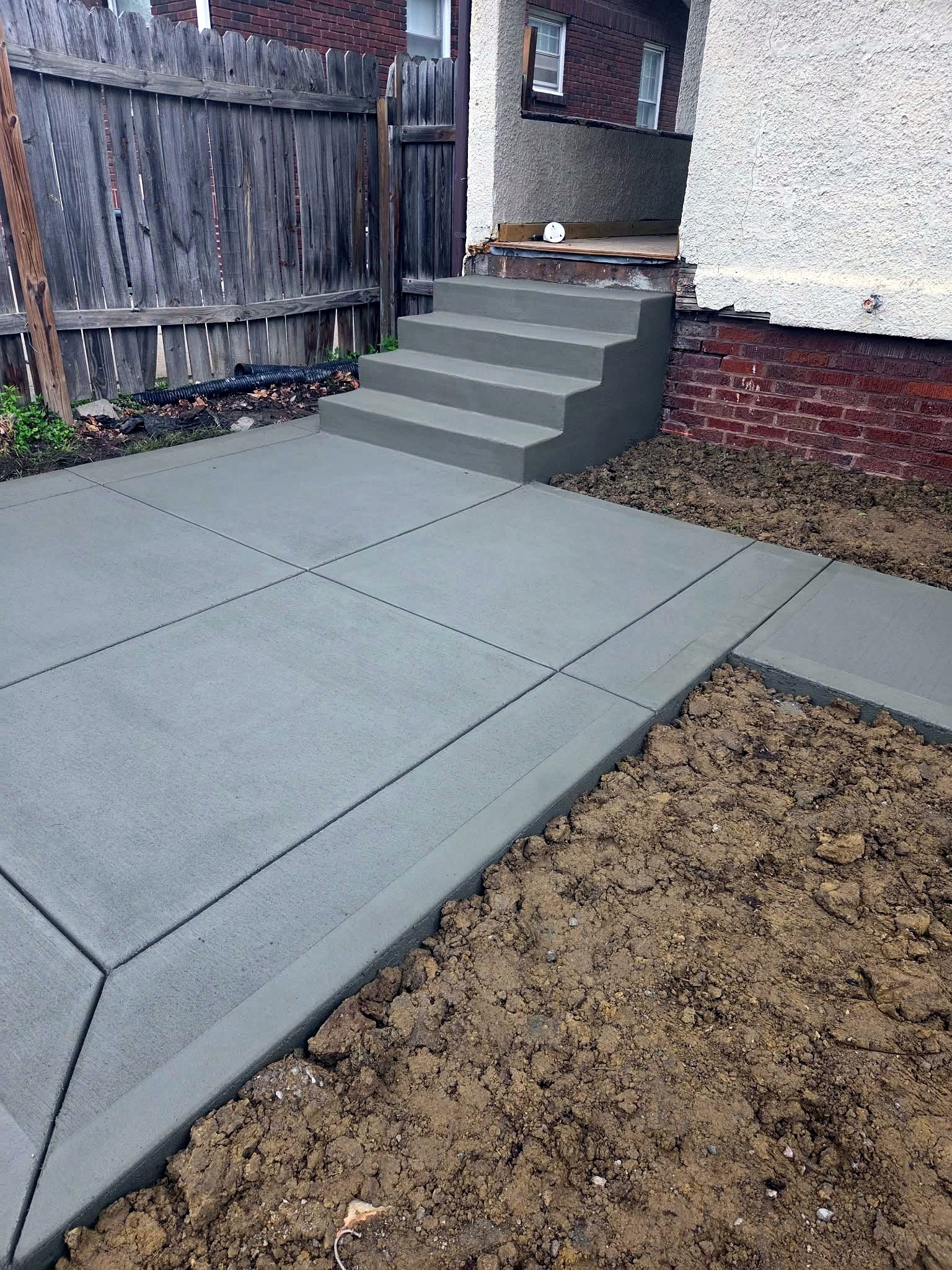 Concrete back steps and walkway finished behind a home